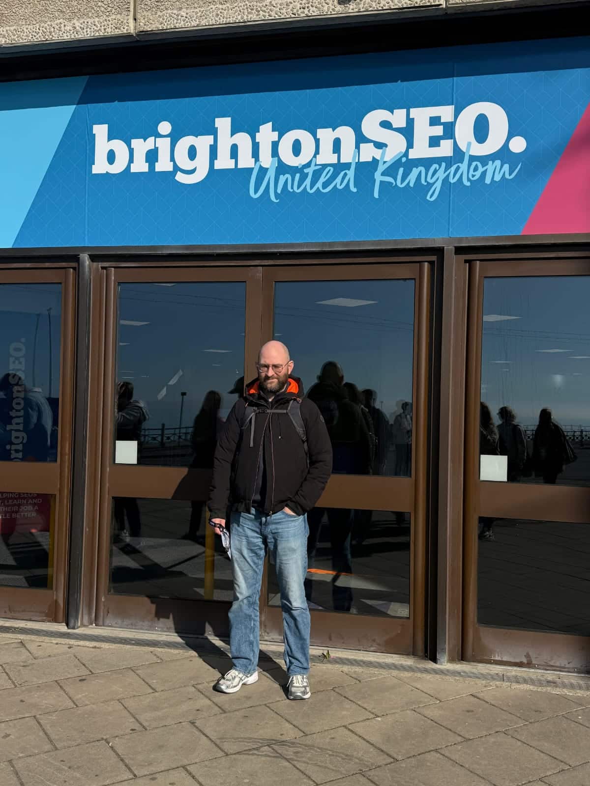 Afbeelding met Ralph Man voor het gebouw waar BrightonSEO logo op staat